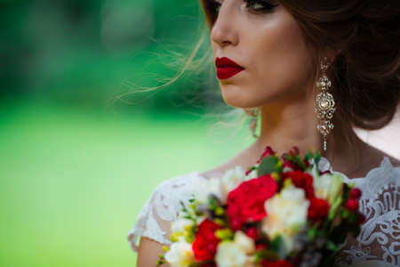 Beautiful bride with a wedding bouquet in her hands outdoors in the park.の写真素材