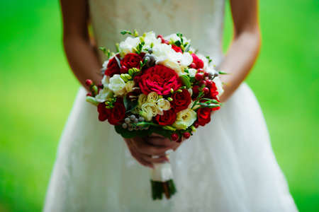 brunette bride in a wedding dress and a bouquet at sunset in the park.の写真素材