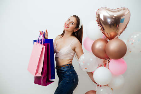 holidays and fashion concept - happy young woman or teenage girl with helium balloons and shoppingの写真素材