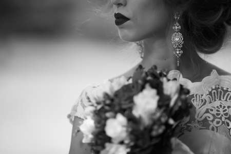 brunette bride in a dress with a wedding bouquet in the park on a background of greenery.