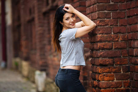 girl in a gray T-shirt smiling in the city.の写真素材