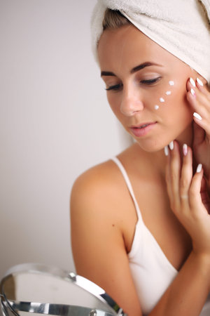 portrait of a beautiful woman applying face cream for skin care