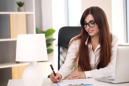 girl working at home with laptop and smiling, brunette in jacketの写真素材