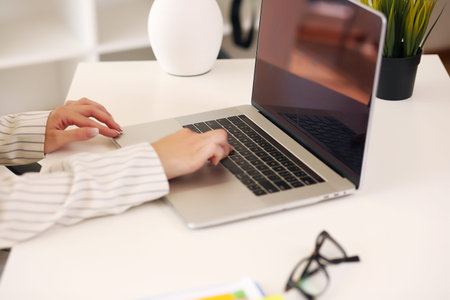 Woman sitting at desk and working at computer hands close up