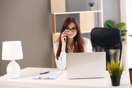young woman taking notes while talking on cell phone.の写真素材