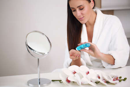 brunette in a bathrobe applied to her hand a health gel for the faceの写真素材
