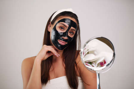 Beautiful woman with a cleansing black mask on her face.の写真素材