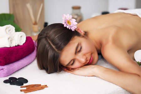 beauty and spa concept - happy woman in spa salon lying on the massage deskの写真素材