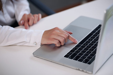 Woman sitting at desk and working at computer hands close up