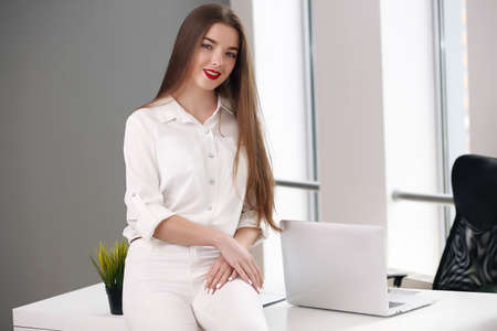 Happy businesswoman leaning on desk in office, office europeの写真素材