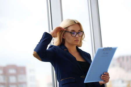 Young blonde businesswoman sitting at desk in the officeの写真素材