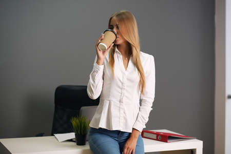 sitting at his desk in the office. Happy business woman sitting in the officeの写真素材