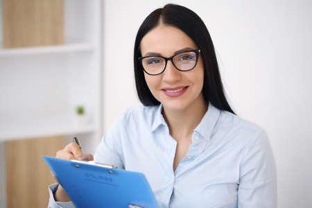 Business woman in shirt using laptop computer and sitting at desk in officeの写真素材
