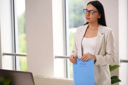 young business lady holding a folder, brunette in a suitの写真素材