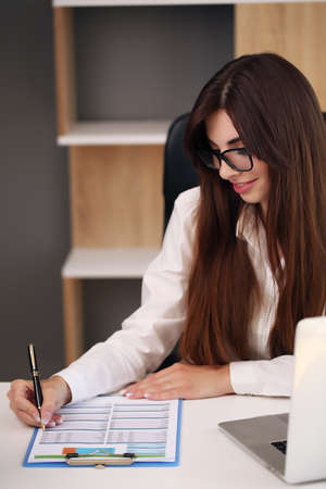 Young pretty brunette business woman with laptop in the officeの写真素材