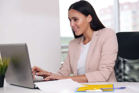 Attractive smiling young girl working on laptop computerの写真素材