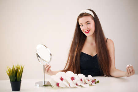 girl admires herself, looking in the mirror close upの写真素材