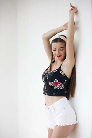 Happy girl in vintage denim shorts standing in confident pose on yellow background.の写真素材