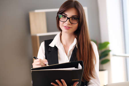 Young pretty brunette business woman with laptop in the officeの写真素材
