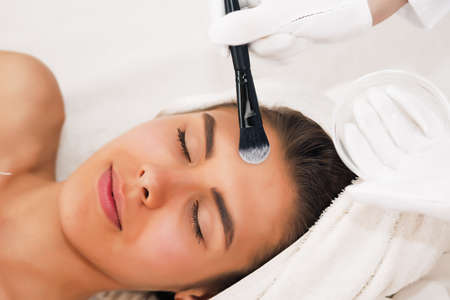 health, beauty, resort and relaxation concept - beautiful woman with closed eyes in spa salon getting massageの写真素材