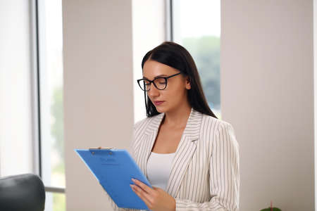 young business lady holding a folder, brunette in a suitの写真素材