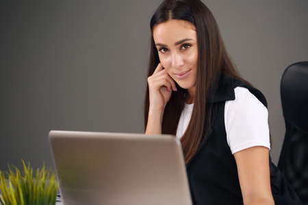 Young happy businesswoman in office, working on laptopの写真素材