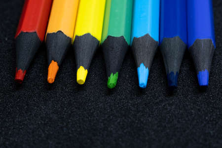 A set of colored pencils in the primary colors of the rainbow for drawing, sketching, labor lessons at school, for creativity, located on a black backgroundの写真素材