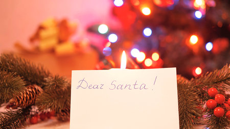 an open craft envelope on a white wooden background , a garland with small lights on the side , a fir twig with red berries , a Christmas concept , a letter to Santa Clausの写真素材