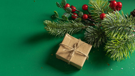green Christmas background with a fir twig, a golden ball and a gift box in eco-packaging with a place for text , the concept of Christmas , black Fridayの写真素材