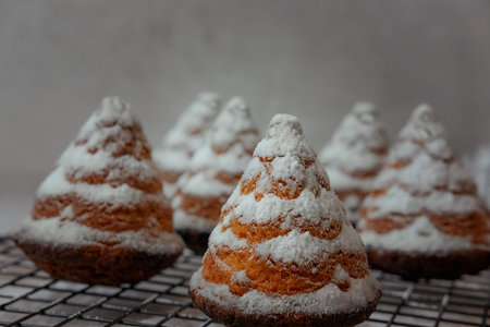 christmas cupcakes in the shape of Christmas trees in powdered sugar on a gray background , flat lei