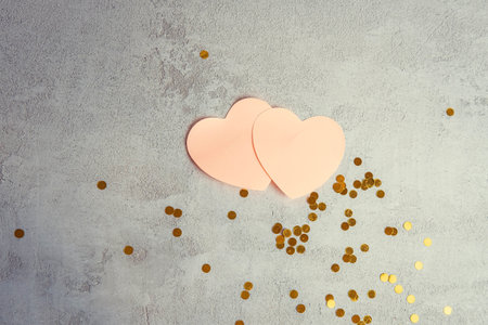 heart-shaped writing papers on a concrete background with sequins , valentines day concept