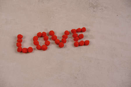 the word love and a heart made of fluffy balls on a red background .the concept of Valentines day and all loversの写真素材