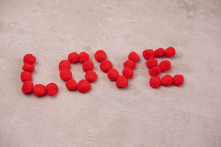 the word love and a heart made of fluffy balls on a red background .the concept of Valentines day and all loversの写真素材