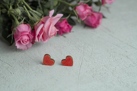 pink roses on a blurry background out of focus and two red hearts , the concept of Valentines Day...