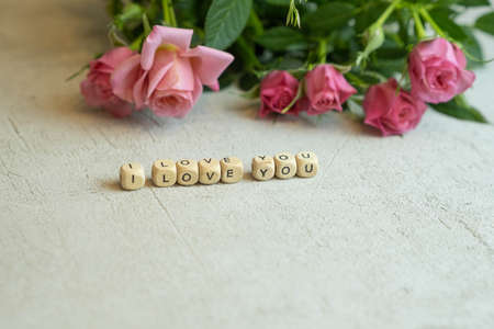 the words I love you from letters on a blurred concrete background with roses out of focus, the concept of Valentines Day and March 8の写真素材