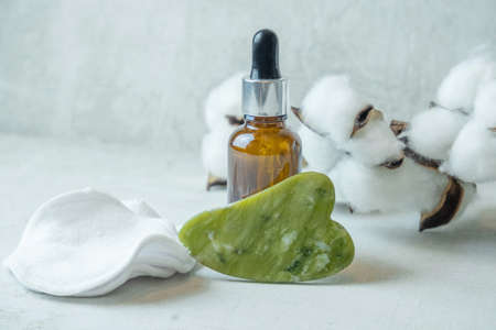 jade roller for facial massage gouache scraper brown bubble with serum , the concept of facial massage and home facial skin careの写真素材