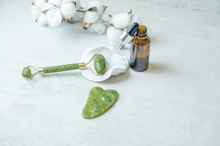 jade roller for facial massage gouache scraper brown bubble with serum , the concept of facial massage and home facial skin careの写真素材