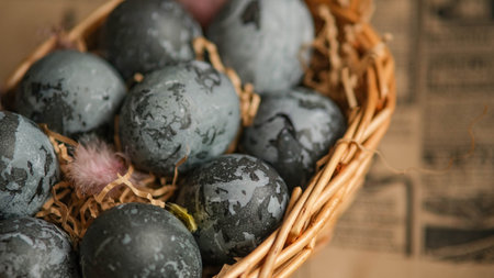 Easter card with a copy of the place for the text. Purple, blue eggs in a basket on a dark newspaper background. Natural dye karkade tea.の写真素材