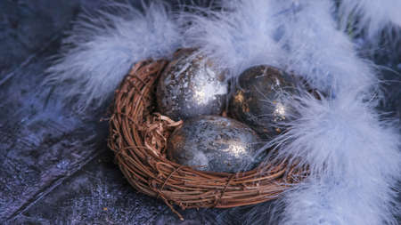 Easter card with a copy of the place for the text. Very Peri 2022 .Purple, blue eggs in a basket on a dark newspaper background. Natural dye karkade tea.の写真素材