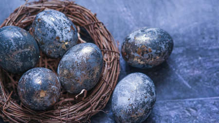 Easter card with a copy of the place for the text. Very Peri 2022 .Purple, blue eggs in a basket on a dark newspaper background. Natural dye karkade tea.の写真素材