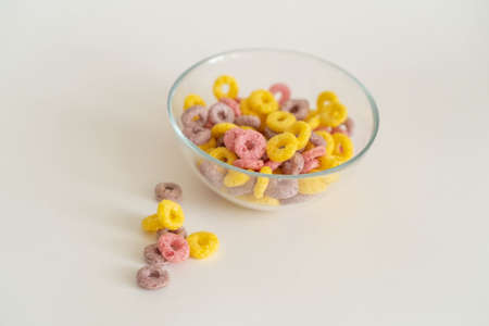 childrens dry breakfast colored corn rings on a white background with a place for textの写真素材
