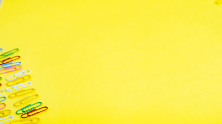 stationery colored paper clips on a yellow background with a place for text