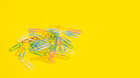 stationery colored paper clips on a yellow background with a place for textの写真素材