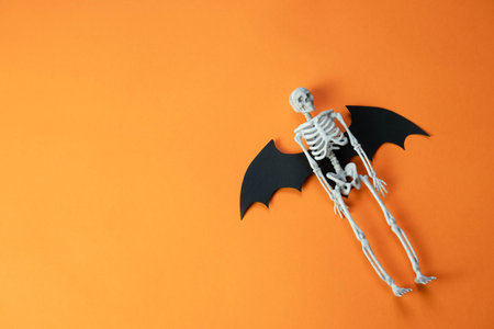 toy skeleton with wings of a flying mouse on an orange background , Halloween concept