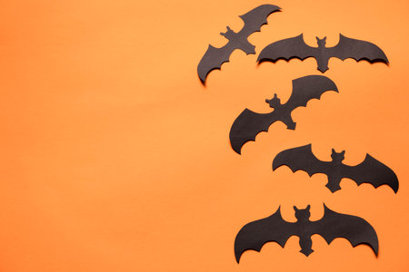 black bats made of colored paper on an orange background , a creative Halloween conceptの写真素材