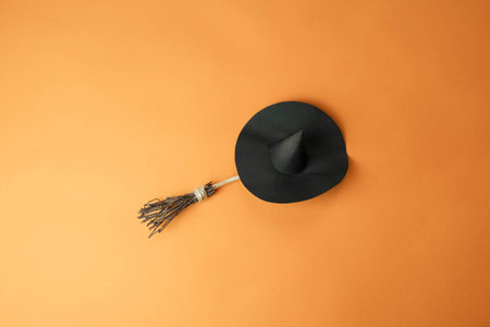 a hat on a witchs broom on an orange background with a place for text, a happy Halloween conceptの写真素材
