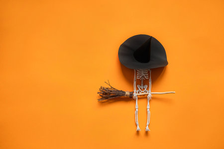 a skeleton with a witchs broom on an orange background , a happy Halloween concept