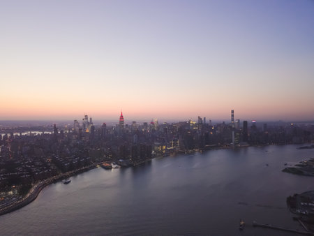 Wide Aerial Drone View of Manhattan Skyline with East River in New York City at Dusk and City Lightsの写真素材