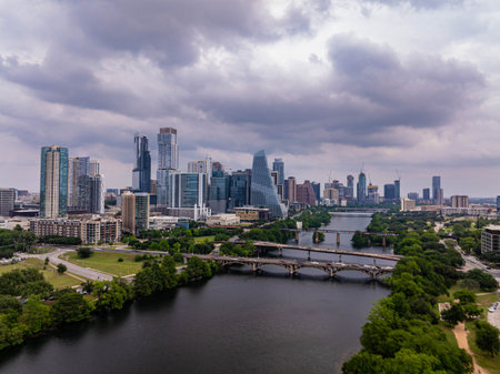 Aerial view of Austin skyline rising majestically above Colorado River, with a dramatic cloudy sky adding a touch of drama to the urban landscapeの写真素材