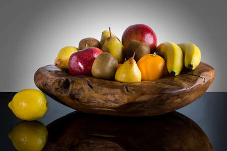Fresh whole fruits in unique custom wood bowl - High quality healthy concept on black and gray backgroundの写真素材